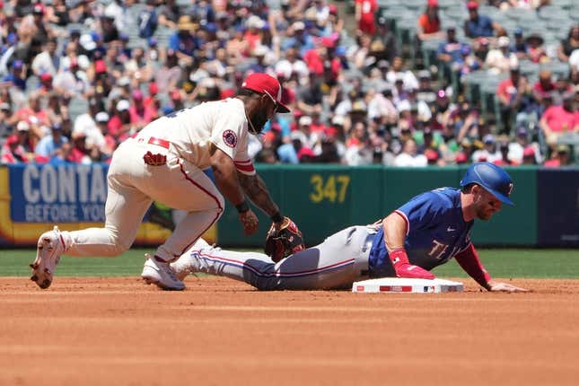 May 7, 2023; Anaheim, California, USA; Texas Rangers right fielder Robbie Grossman (4) slides beneath the tag of Los Angeles Angels second baseman Luis Rengifo (2) into second base in the first inning at Angel Stadium.