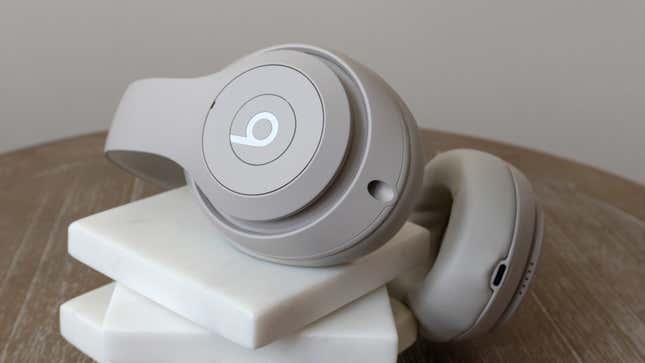 The Beats Studio Pro wireless headphones sitting on a stack of white marble coasters atop a wooden table.