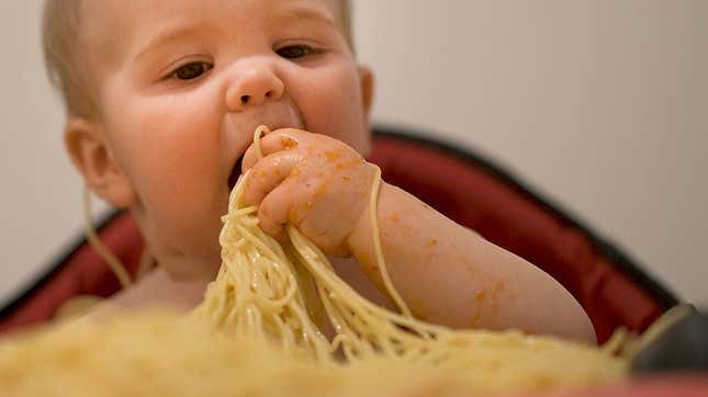 Baby eating spaghetti with hands