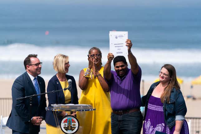 Anthony Bruce, second from right, a great-great grandson of Charles and Willa Bruce, holds up the title deed of the oceanfront property known as Bruce’s Beach during a dedication ceremony in Manhattan Beach, Calif., Wednesday, July 20, 2022, as he is joined by wife, Sandra, from right, Los Angeles County officials, Holly J. Mitchell, Janice Hahn and Dean Logan. Los Angeles County officials on Wednesday presented the deed to prime California oceanfront property to heirs of the Black couple who built a beach resort for African Americans but were harassed and finally stripped of the land nearly a century ago. 