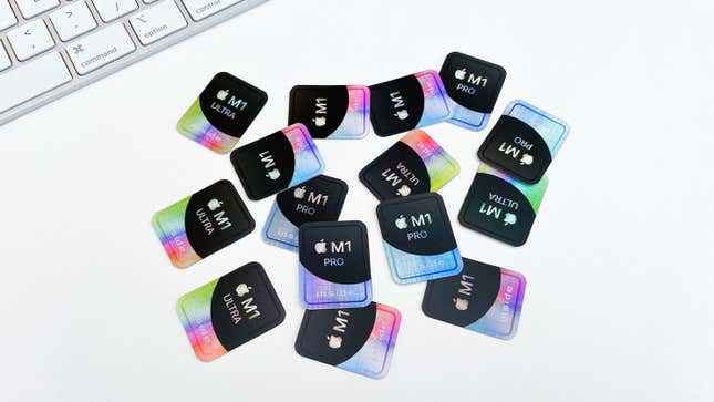A pile of Apple Inside stickers on a white desktop with an Apple keyboard visible in the corner.