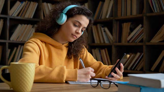 Teen girl studying and using app on smartphone