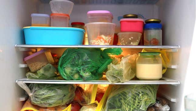 Refrigerator full of containers, produce bags, and condiments