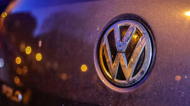 A dirty trademark of the car manufacturer Volkswagen is covered with drops of water at dawn.