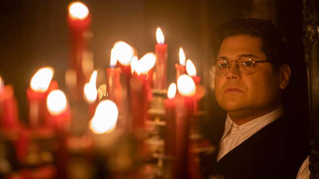 Harvey Guillén as Guillermo, standing beside a bunch of candles.