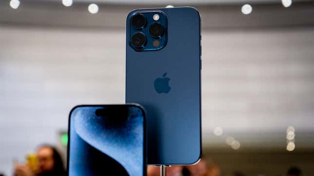 The iPhone 15 Pro in blue with a blurred background and people standing around.