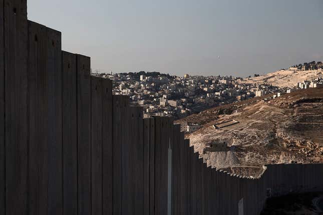 The golden Dome of the Rock (C) in Jerusalem's old city is seen in the distance beyond a section of the controversial Israeli barrier in the West Bank city of Abu Dis, October 29 , 2014. The Dome of the Rock is situated within the Al-Aqsa compound, known to Muslims as Noble Sanctuary and to Jews as Temple Mount. On the 25th anniversary of the fall of the Berlin Wall, there are still barriers separating communities around the world, from the barbed wire fence dividing the two Koreas, the fence around the Spanish enclave of Melilla, to the sectarian Peace Wall in Belfast, the Israel-Gaza barrier and the border separating Mexico from the United States. Picture taken October 29, 2014. REUTERS/Finbarr O'Reilly (WEST BANK - Tags: ANNIVERSARY CIVIL UNREST POLITICS SOCIETY) ATTENTION EDITORS: PICTURE 15 OF 28 FOR WIDER IMAGE PACKAGE 'THE WALLS THAT DIVIDE' TO FIND ALL IMAGES SEARCH 'WALLS DIVIDE' - RTR4D2VJ
