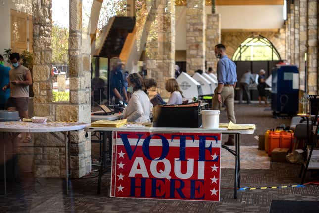 Poll workers help voters inside a polling location on October 13, 2020 in Austin, Texas.
