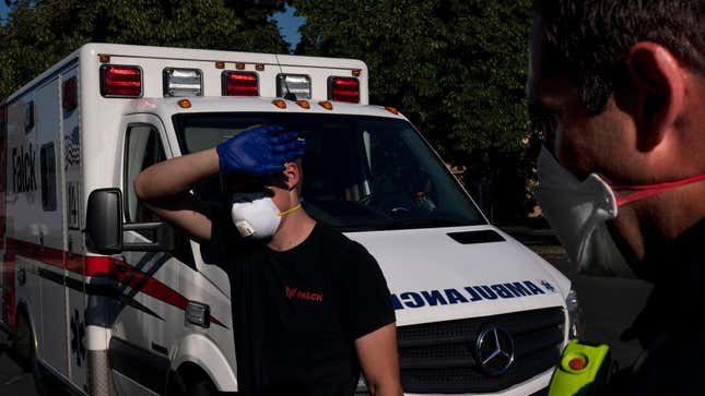 A paramedic shields his eyes while treating a man experiencing heat exposure during a heat wave, Saturday, June 26, 2021, in Salem, Oregon.