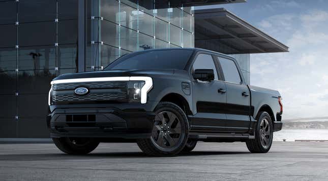 A black 2023 Ford F-150 Lightning is parked in front of a glass building.