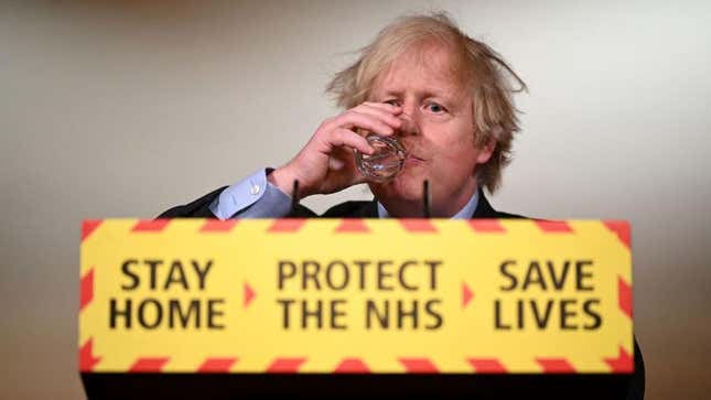 Boris Johnson drinking beverage over sign that reads "Stay Home, Save Lives"