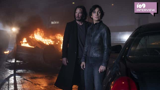 Neo and Trinity standing in front of a burning car.