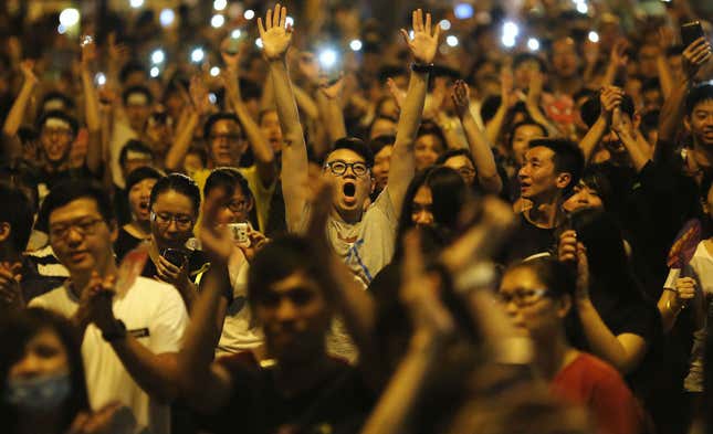 Protesters react as Joshua Wong (not pictured), leader of the student movement, speaks to the crowd outside the government headquarters building in Hong Kong October 1, 2014. Protesters react as Joshua Wong (not pictured), leader of the student movement, speaks to the crowd outside the government headquarters building in Hong Kong October 1, 2014.