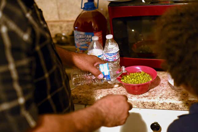 ACKSON, MS - DECEMBER 8: Charles Wilson III prepares a bowl of peas with bottled water for his son Charles Wilson V at their home December 8, 2022 in Jackson, Mississippi