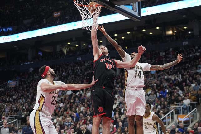 Feb 23, 2023; Toronto, Ontario, CAN; Toronto Raptors center Jakob Poeltl (19) tips in a ball against New Orleans Pelicans forward Brandon Ingram (14) and  forward Larry Nance Jr. (22) during the first half at Scotiabank Arena.
