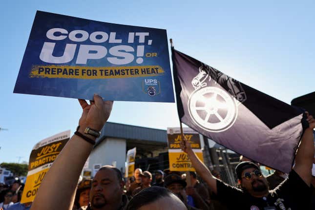 People hold placards during a rally, one reads "Cool it, Ups! Or prepare for Teamster heat."