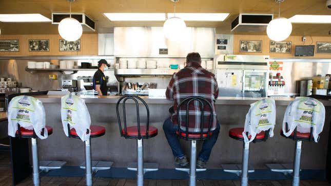 A man sits at a Waffle House counter surrounded by seats bagged up for social distancing purposes