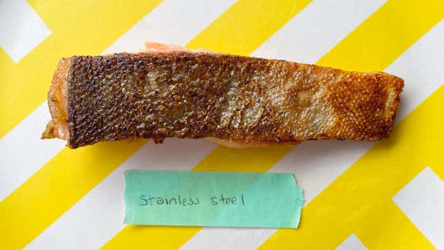 A piece of cooked fish with visibly crispy skin on a table above a label that reads "stainless steel"