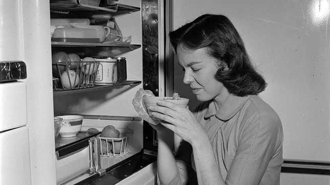 Woman sniffing moldy food from fridge