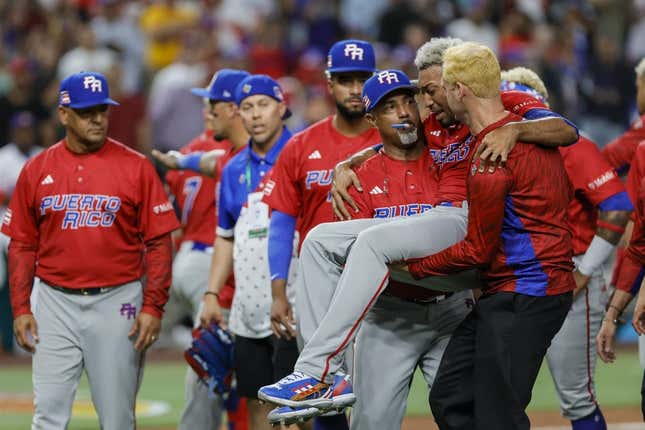 Mar 15, 2023; Miami, Florida, USA; Puerto Rico pitcher Edwin Diaz (39) gets taken off the field by pitching coach Ricky Bones (27) after an apparent leg injury during the team celebration against Dominican Republic at LoanDepot Park.