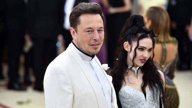Elon Musk stands next to Grimes at an event.