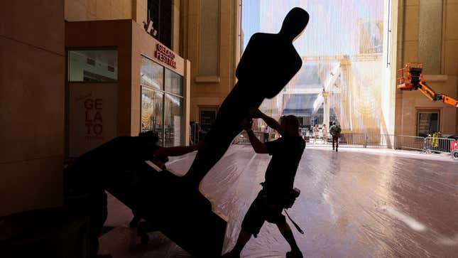 A person wheels a massive Oscar statue.