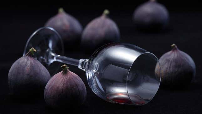 Figs surrounding empty overturned glass of red wine