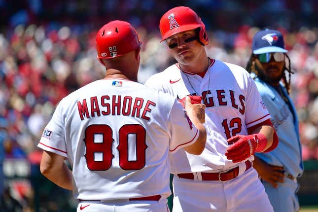 Apr 9, 2023; Anaheim, California, USA; Los Angeles Angels right fielder Hunter Renfroe (12) is greeted by first base coach Damon Mashore (80) after hitting a single against the Toronto Blue Jays during the third inning at Angel Stadium.