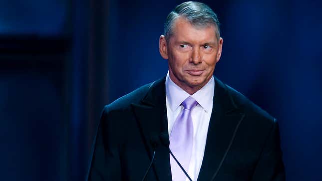Vince McMahon smirks while standing at a podium at WWE's 25th anniversary Hall of Fame ceremony. 