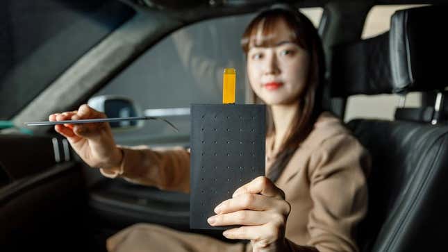A person holds an LG Thin Actuator Sound Solution panel, demonstrating its size
