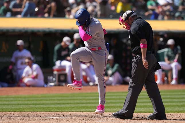 May 14, 2023; Oakland, California, USA; Texas Rangers right fielder Adolis Garcia (center) steps on home plate after hitting a grand slam home run against the Oakland Athletics as home plate umpire Dan Bellino (right) watches during the eighth inning at Oakland-Alameda County Coliseum.