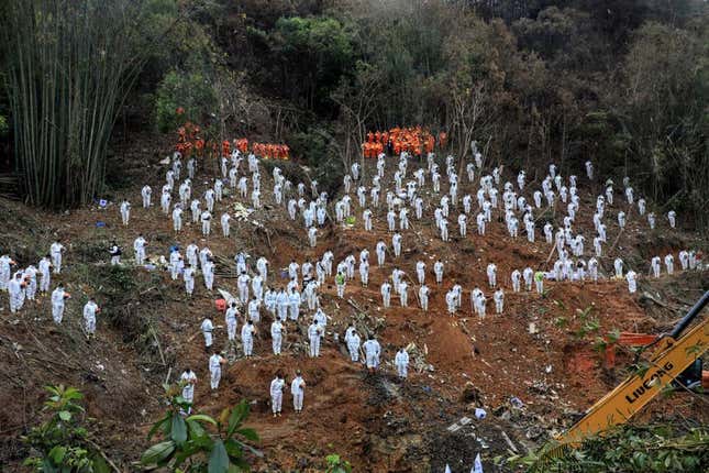 Esta foto, tomada el 27 de marzo de 2022, muestra a los rescatistas de pie en un tributo en silencio por las víctimas en el lugar del accidente aéreo de China Eastern Airlines en el condado de Tengxian, ciudad de Wuzhou, en la región sureña de Guangxi en China. - El Boeing 737-800 volaba entre las ciudades de Kunming y Guangzhou el 21 de marzo cuando cayó en picado contra la ladera de una montaña, se desintegró en el impacto y mató a las 132 personas a bordo.