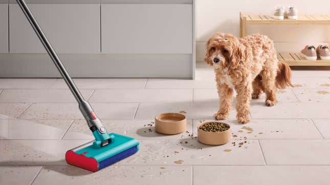 El cabezal de limpieza húmeda Dyson Submarine se usa en un piso de baldosas para limpiar comida derramada y huellas de patas de un perro pequeño.