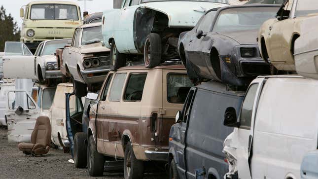 A photo of old cars in a junk yard. 