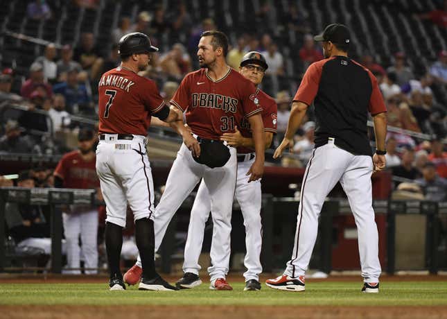 Caleb Smith #31 of the Arizona Diamondbacks is restrained by first base coach Robby Hammock #7 and third base coach Tony Perezchica #3 after having his glove confiscated during the eighth inning against the Philadelphia Phillies at Chase Field