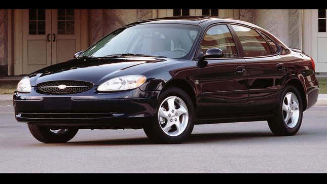 A black Ford Taurus parked in front of a building. 