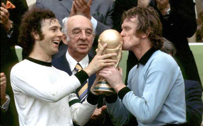 Captain Franz Beckenbauer (left) handing the FIFA World Cup trophy to goalkeeper Sepp Maier (right)