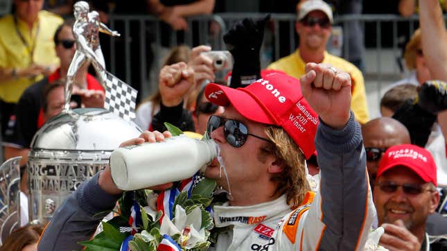 2011 Indy 500 Dan Wheldon sips from the traditional bottle of Victory Circle milk. The Borg-Warner trophy is in the background.
