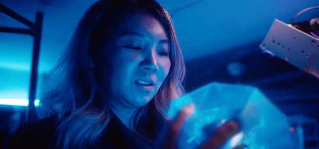 A woman stares into a glowing blue sphere.