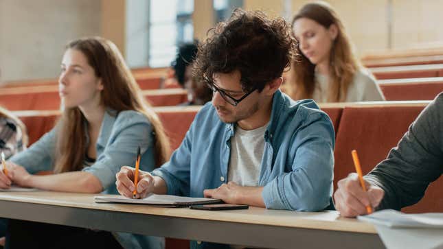 College students taking handwritten notes during lecture