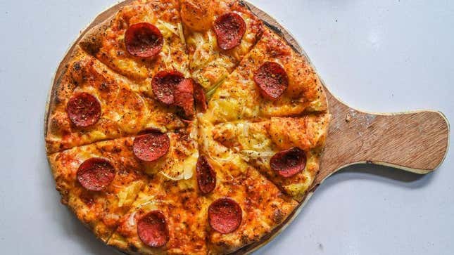 Pepperoni pizza on cutting board against a white background