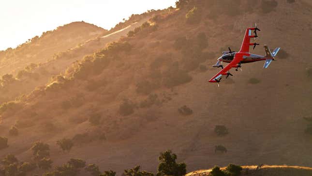 The kittyhawk Heaviside red and silver air taxi flying off toward a sunset