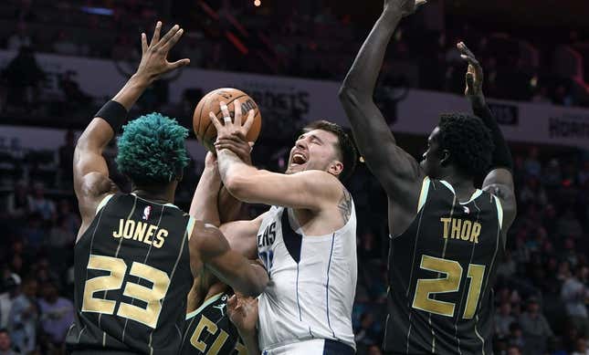 Mar 26, 2023; Charlotte, North Carolina, USA;  Dallas Mavericks guard Luka Doncic (77) shoots as he is defended by Charlotte Hornets forward center Kai Jones (23) and forward JT Thor (21) during the first half at the Spectrum Center.
