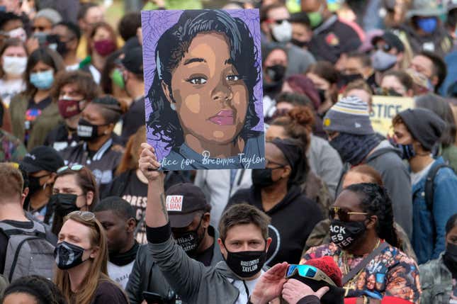  A protestor brandishes a portrait of Breonna Taylor during a rally in remembrance of the one-year anniversary of her death in Louisville, Kentucky, on March 13, 2021. - Twelve months after the killing — in which police shot Taylor while looking for a former friend of hers — only one of three police officers has been charged, and only for endangering Taylor’s neighbors by firing wildly. 