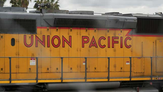 A yellow Union Pacific train car sits under a cloudy sky in California. The words Union Pacific are outlined in black, the inside painted red. 