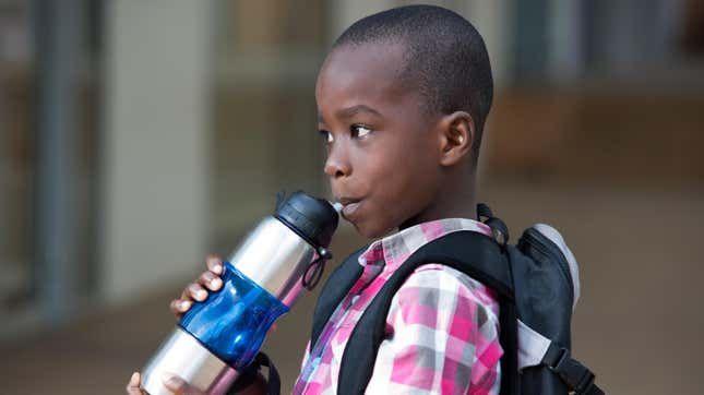 Child drinking from water bottle at school.