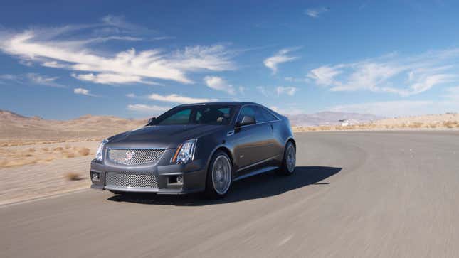 A photo of a silver Cadillac CTS-V coupe driving on a track. 
