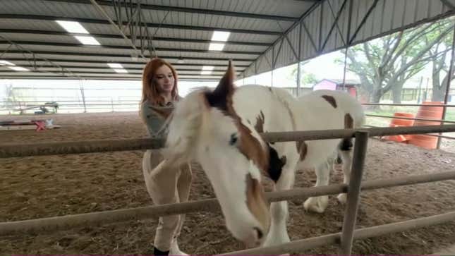 Kaitlyn Siragusa se gratte derrière l'oreille d'un cheval dans une vidéo YouTube d'avril 2023.