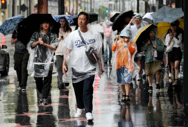 People walk through strong winds and rain on Hollywood Boulevard during Tropical Storm Hilary, on August. 20, 2023, in Los Angeles.
