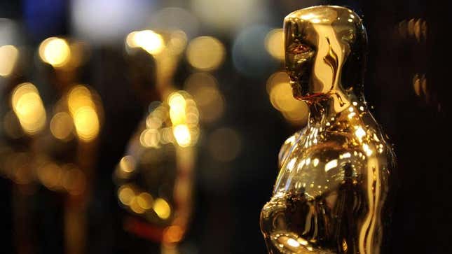 An Oscar statue against a black and gold bokeh background; additional statuettes are in the back, although they are out of focus.